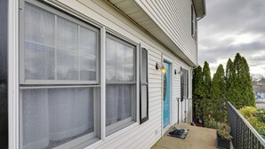 Una casa con ventanas amplias, una puerta azul y un pequeño porche con barandilla.