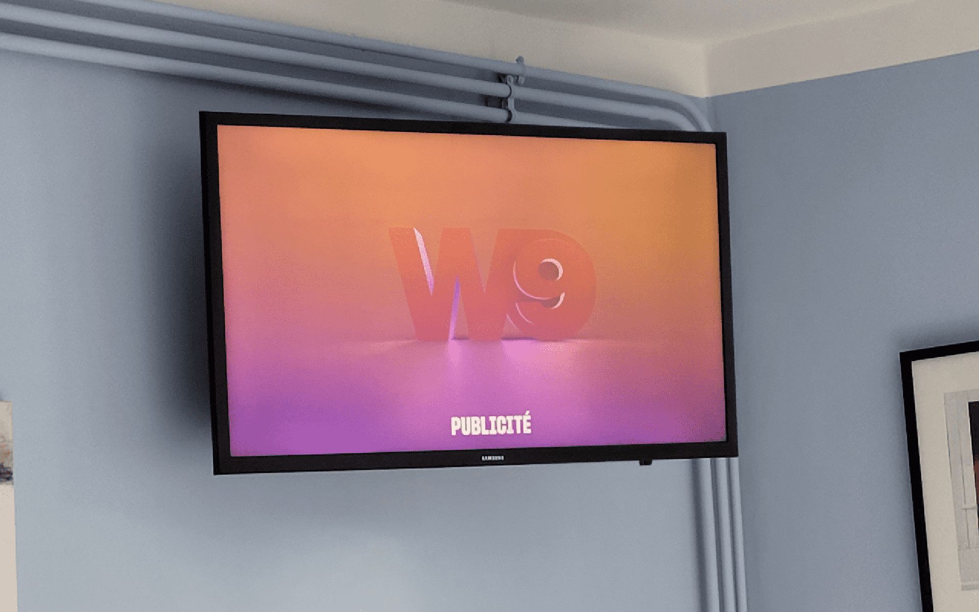 A flat-screen TV mounted on a wall with a gradient background.