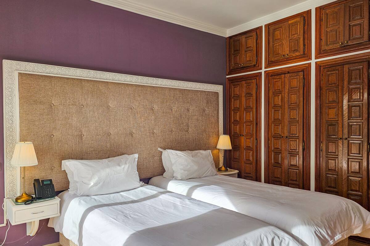 A double bed with a headboard, two bedside tables with lamps, and a large wooden wardrobe.