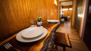 Un interior de madera con una mesa de comedor para dos, una planta pequeña y un florero.