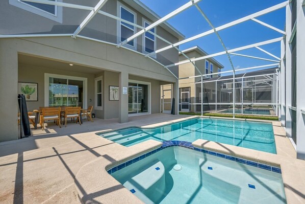 A pool area with a sunken hot tub, wooden deck chairs, and a glass-enclosed patio. - Last Minute Disney! Private Pool, Hot Tub & Themed Bedrooms. Book Now! #104249 (Orlando)
