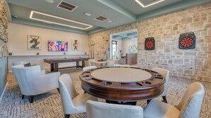 A modern room with a round table, comfortable seating, a dartboard, and artwork on the walls.