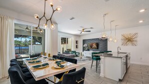 Une cuisine moderne dotée d’un îlot central, de chaises noires et d’une table à manger pouvant accueillir six personnes.