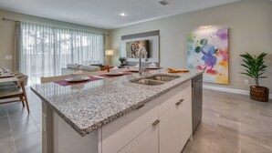 A modern kitchen with granite countertops, a built-in sink, and a dining area with a table and chairs.