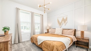 A bedroom with a large bed, a wooden nightstand, a wall-mounted lamp, and a ceiling light fixture.