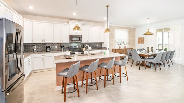 A modern kitchen with white cabinets, a central island, and bar stools.