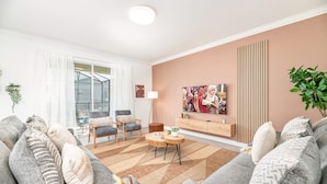 A modern living room with a sofa set, a coffee table, and a TV mounted on the wall.