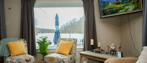 A cozy living room with two armchairs, a small table, and a television mounted on the wall.