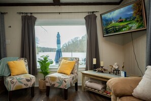 A cozy living room with two armchairs, a small table, and a television mounted on the wall.