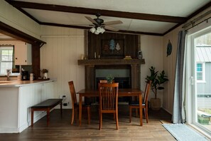 Un comedor con una mesa y sillas de madera, un ventilador de techo y vistas al exterior a través de una ventana.