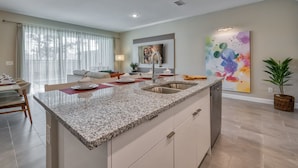 A modern kitchen with granite countertops, a built-in sink, and a dining area with a table and chairs.