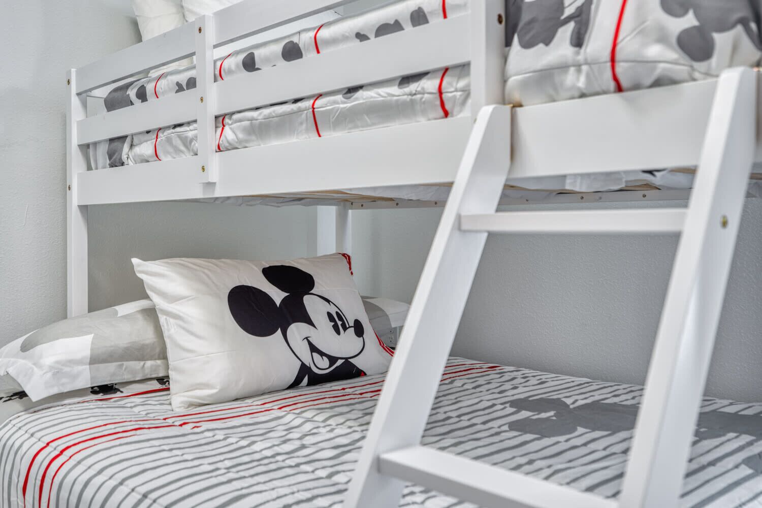 A bunk bed with a Mickey Mouse pillow and striped bedding.