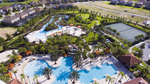 Vue aérienne d’un complexe hôtelier doté de plusieurs piscines, de palmiers et d’un court de tennis.