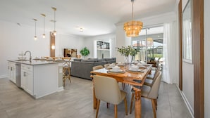 A modern kitchen with a central island, dining area with a wooden table and chairs, and a cozy living space with a gray sofa. - Last Minute Disney Getaway! Townhouse with Private Pool. Book Now! #98615 (Orlando)