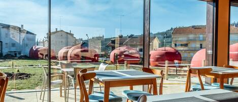 Un restaurante con grandes ventanales, mesas y sillas de madera.