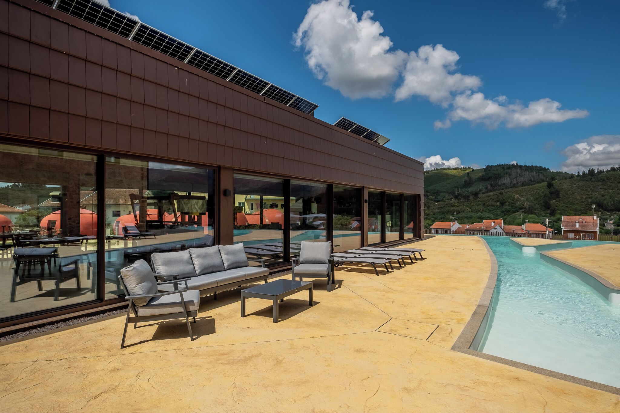 Ein Poolbereich auf dem Dach mit Liegestühlen und Blick auf eine Berglandschaft.