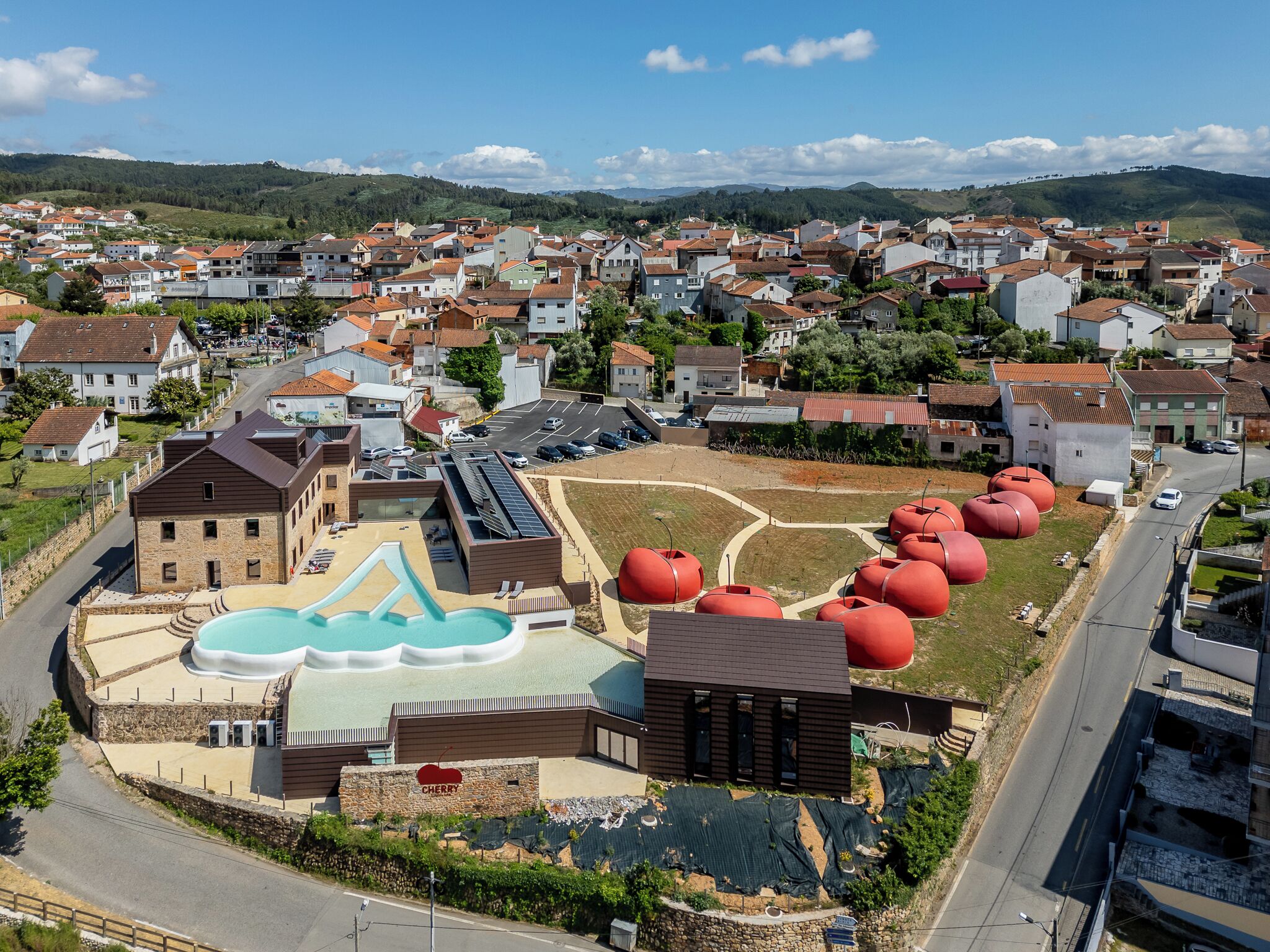 A residential area with a swimming pool, a building with a cherry logo, and several large red tanks.