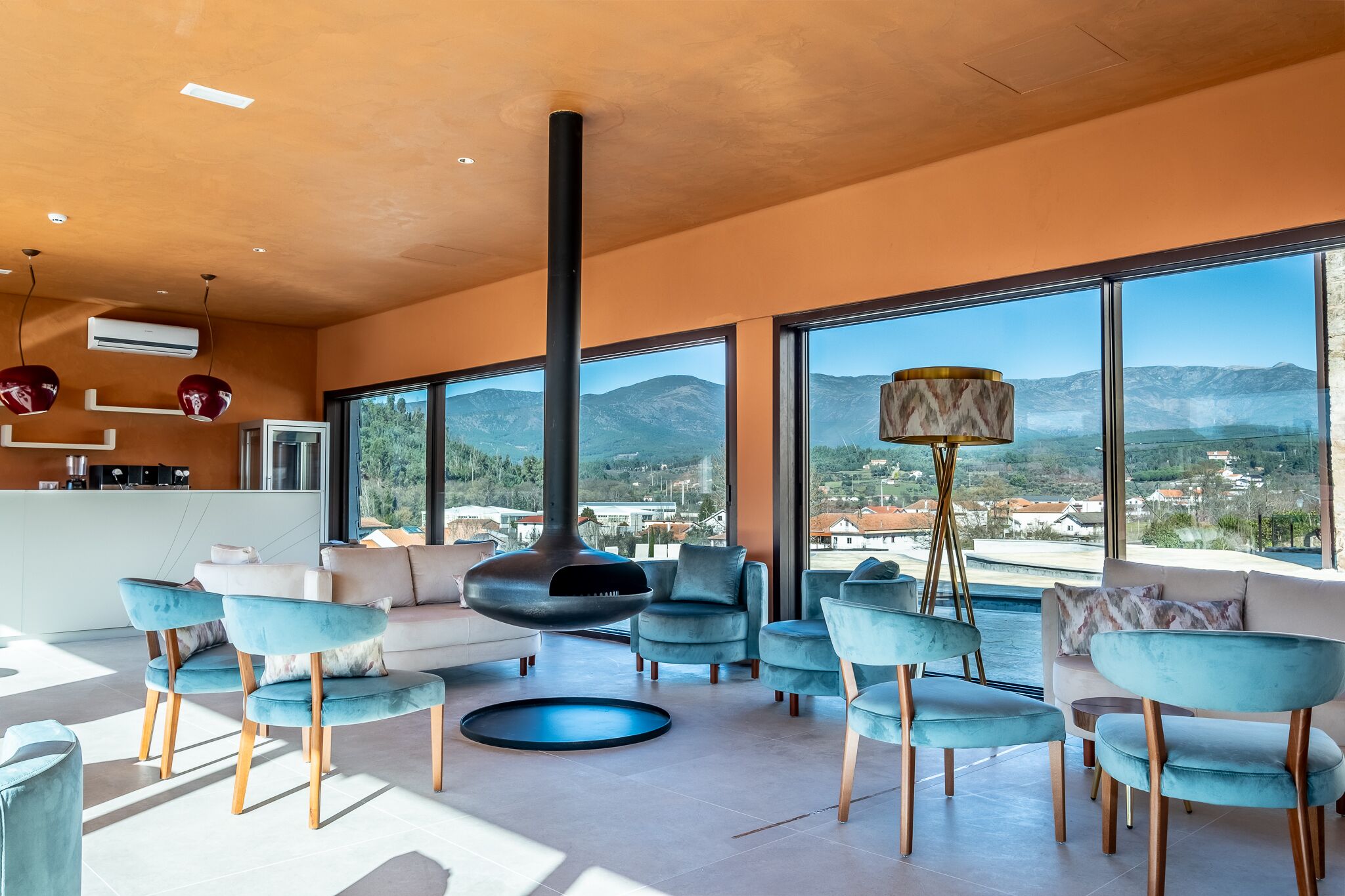 A modern living room with a large fireplace, comfortable seating, and a view of mountains through large windows.