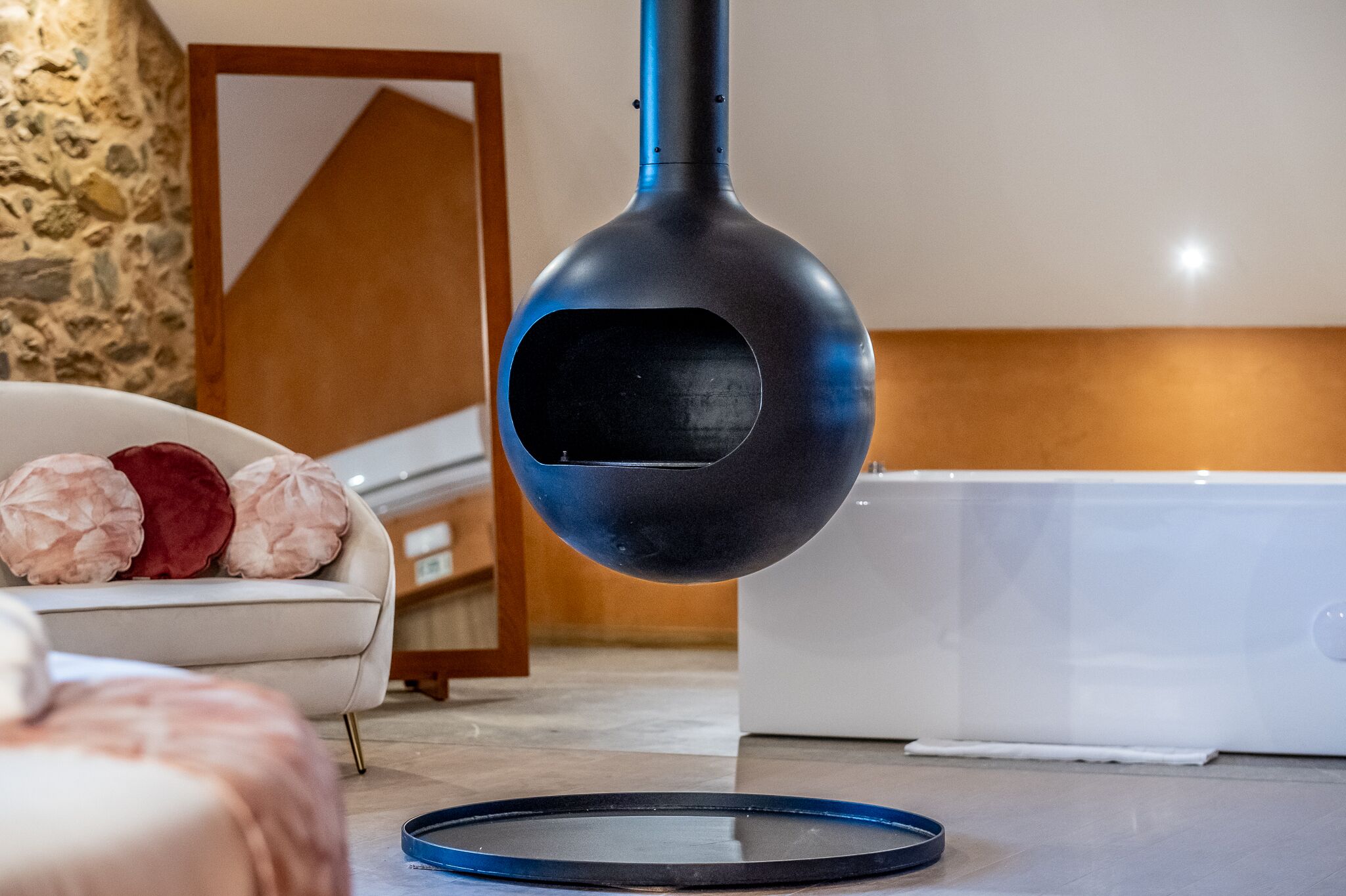 Ein modernes Zimmer mit Steinwand, einem weißen Sofa und einem blauen, runden Objekt auf dem Boden.