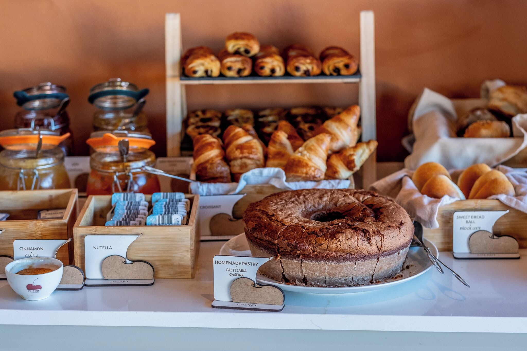 A variety of baked goods including pastries, a chocolate cake, and jars of spreads.