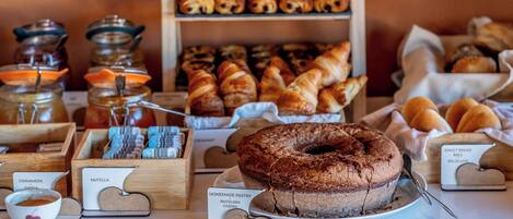 Un assortiment de produits de boulangerie, notamment des pâtisseries, un gâteau au chocolat et des pots de confitures et de pâtes à tartiner.