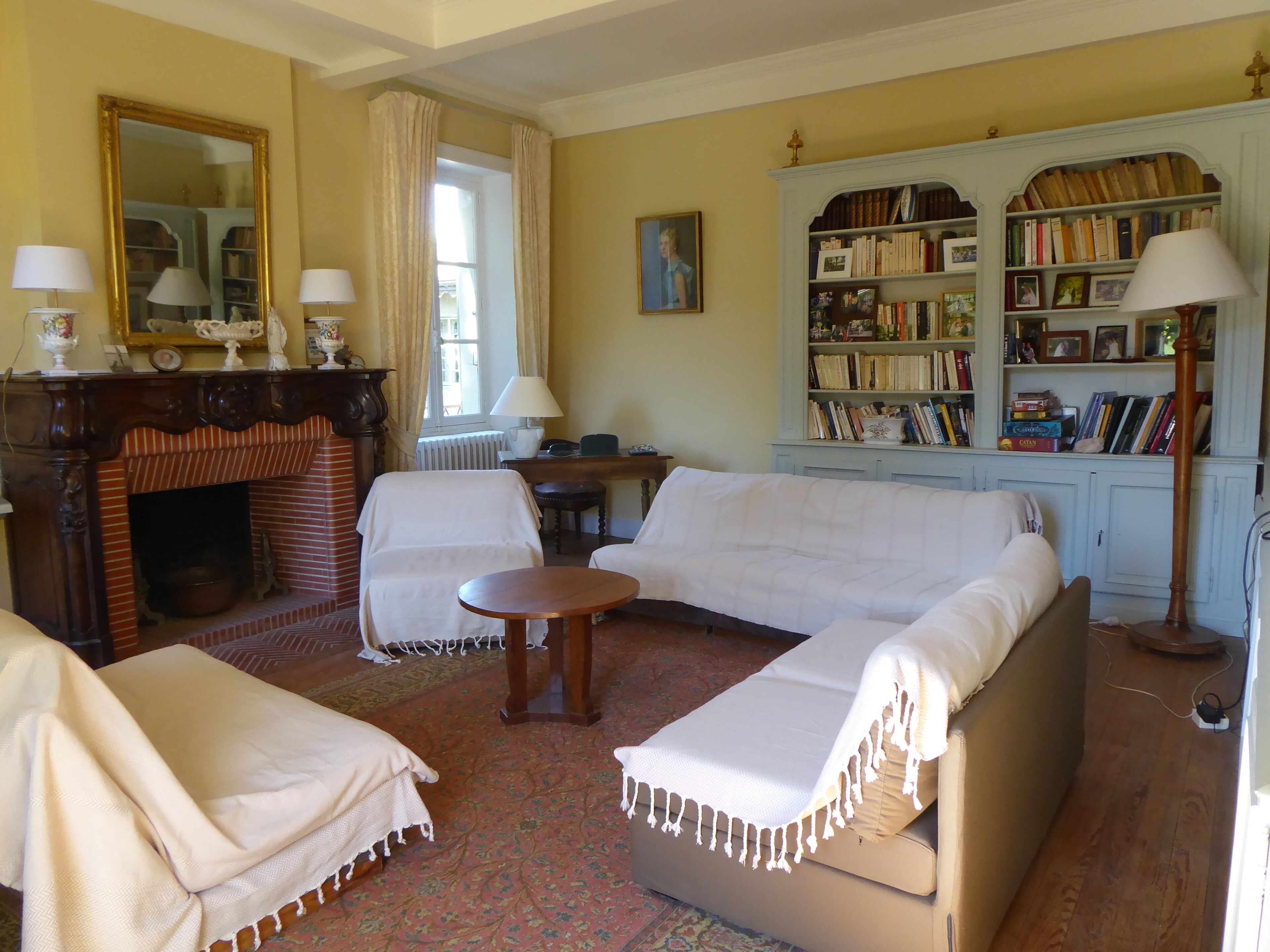A living room with a fireplace, a sofa, a chair, a small table, and a bookshelf filled with books.