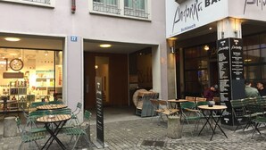 Een terras met tafels en stoelen, een boekhandel en een bar met een menubord.