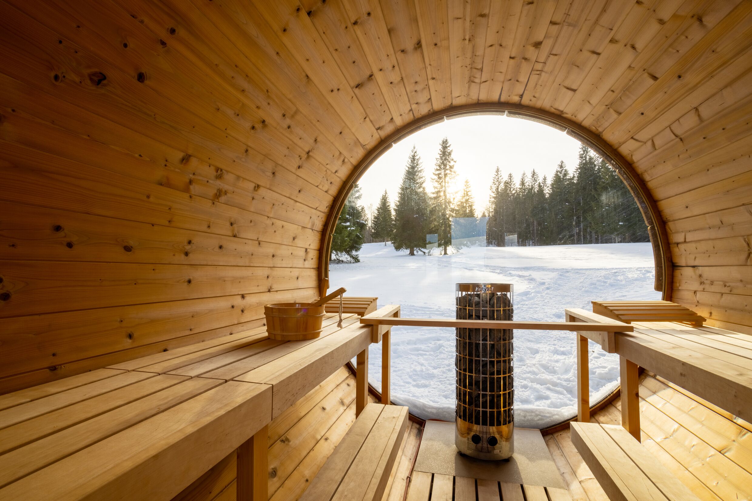 Eine Holzsauna mit Bänken und Blick auf eine verschneite Landschaft.