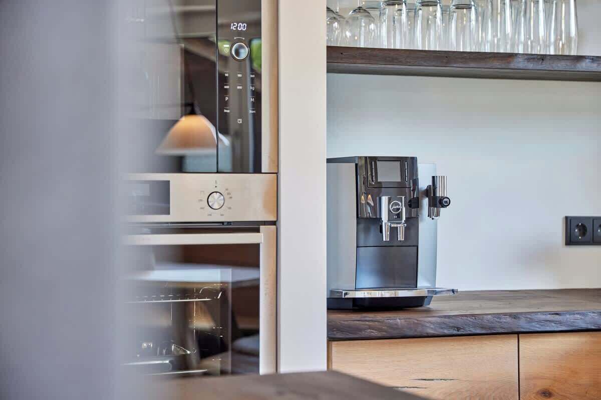 Eine Küche mit Kaffeemaschine, Mikrowelle und einem Glaskasten mit Gläsern.