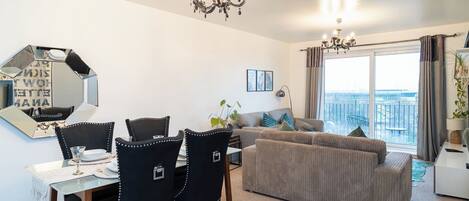 A modern living room with a dining area, a sofa, and a large window with a view.