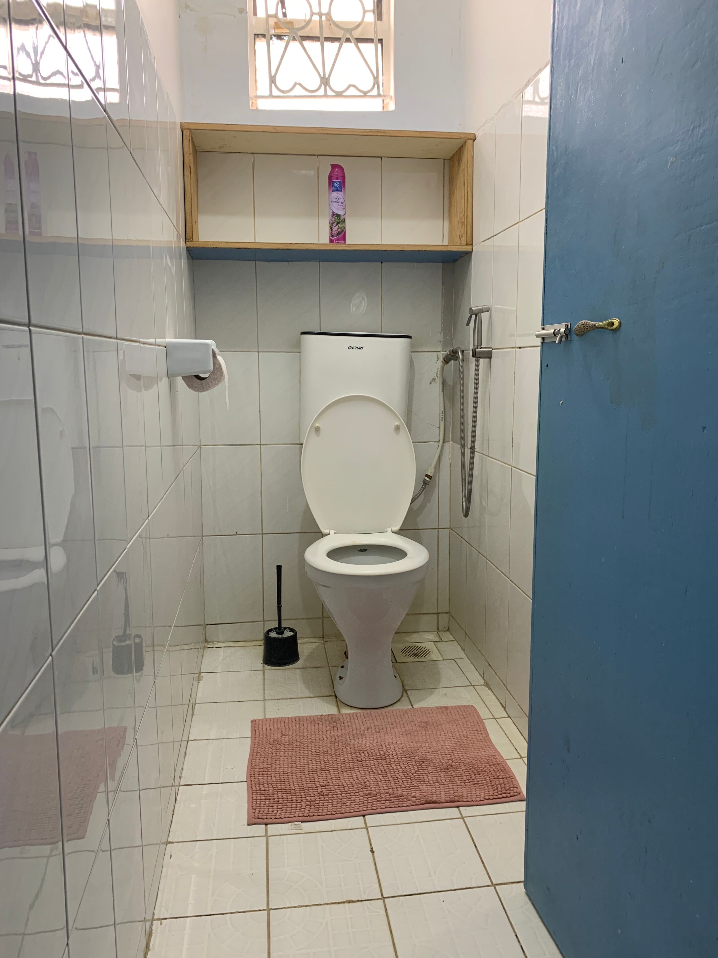 A small bathroom with a toilet, a shower, and a window.