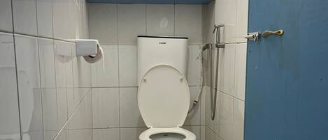 A small bathroom with a toilet, a shower, and a window.