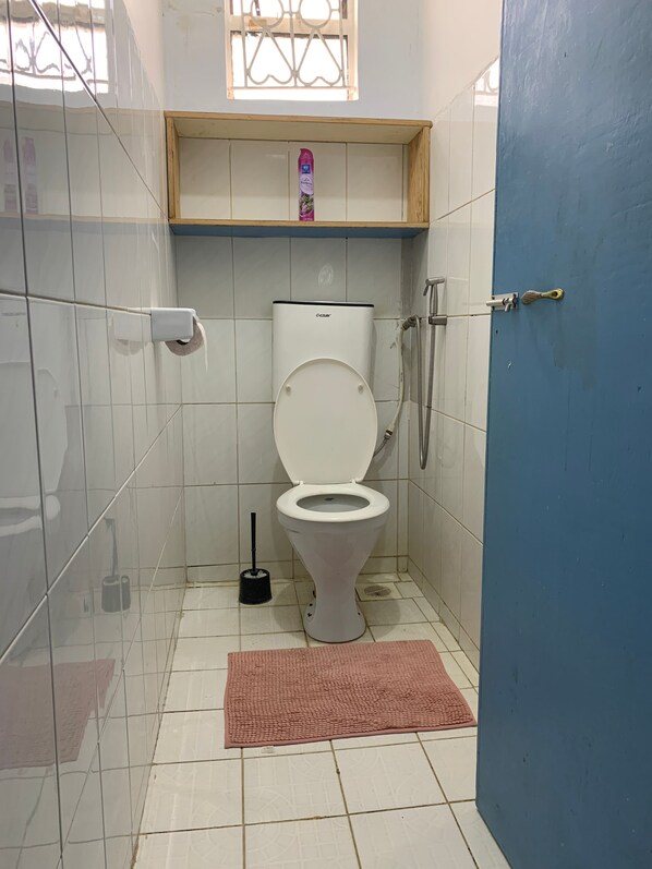 Un baño pequeño con inodoro, ducha y ventana.