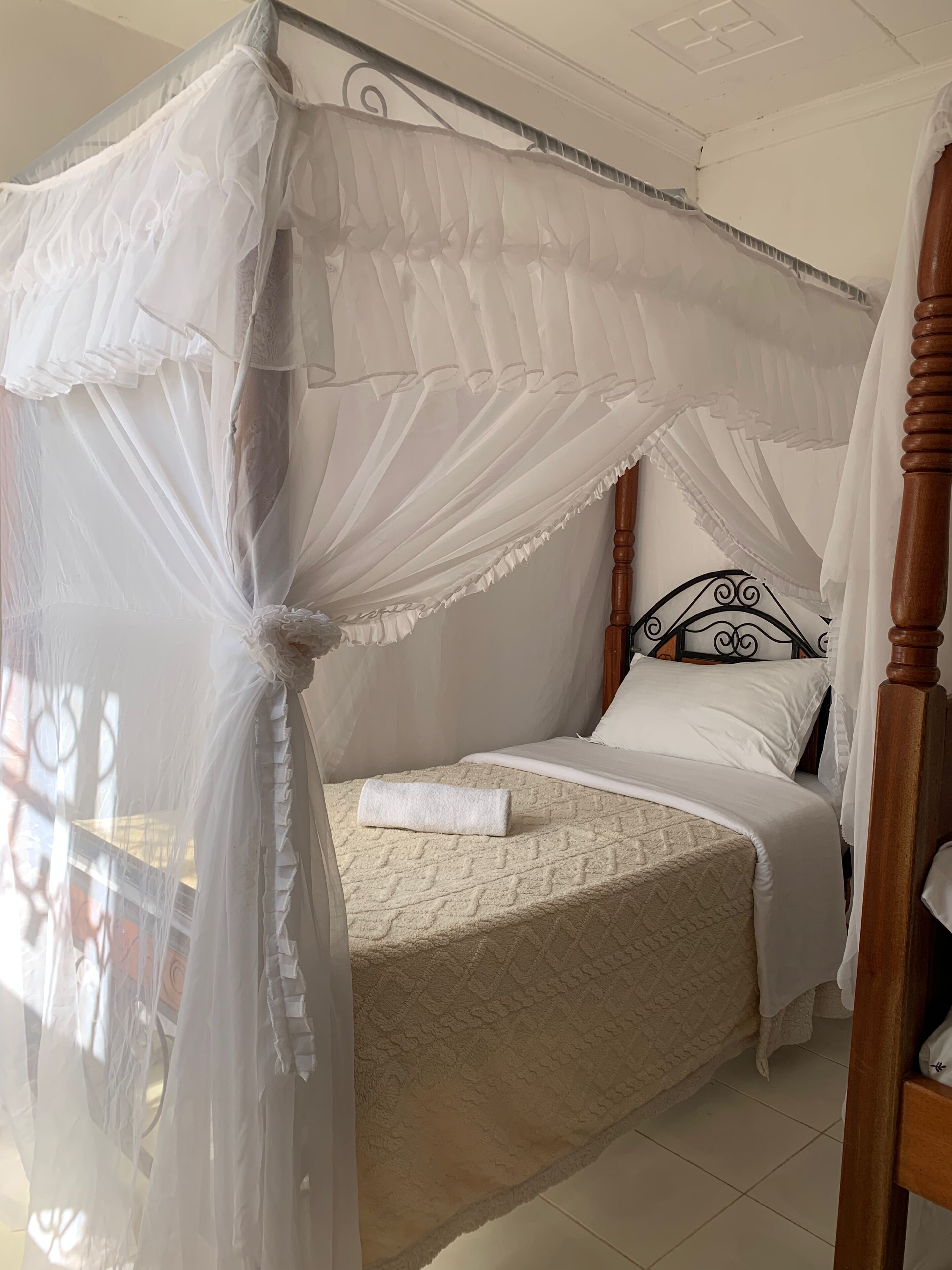 A bed with a canopy, a wooden headboard, and a white bedspread.