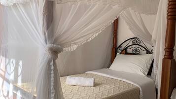 A bed with a canopy, a wooden headboard, and a white bedspread.