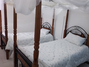 A room with two wooden four-poster beds with white bedding and small floral patterns. - Nairobi Transit Lounge (Syokimau)