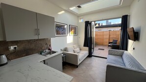 Un espace de vie compact comprenant un coin cuisine, un canapé, une table à manger et une vue sur l’extérieur.