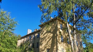 A large, multi-story building with a beige facade, surrounded by lush greenery and trees. - Beautiful 2 Bed Apartment Sauna Facility in Kotka (Kotka)
