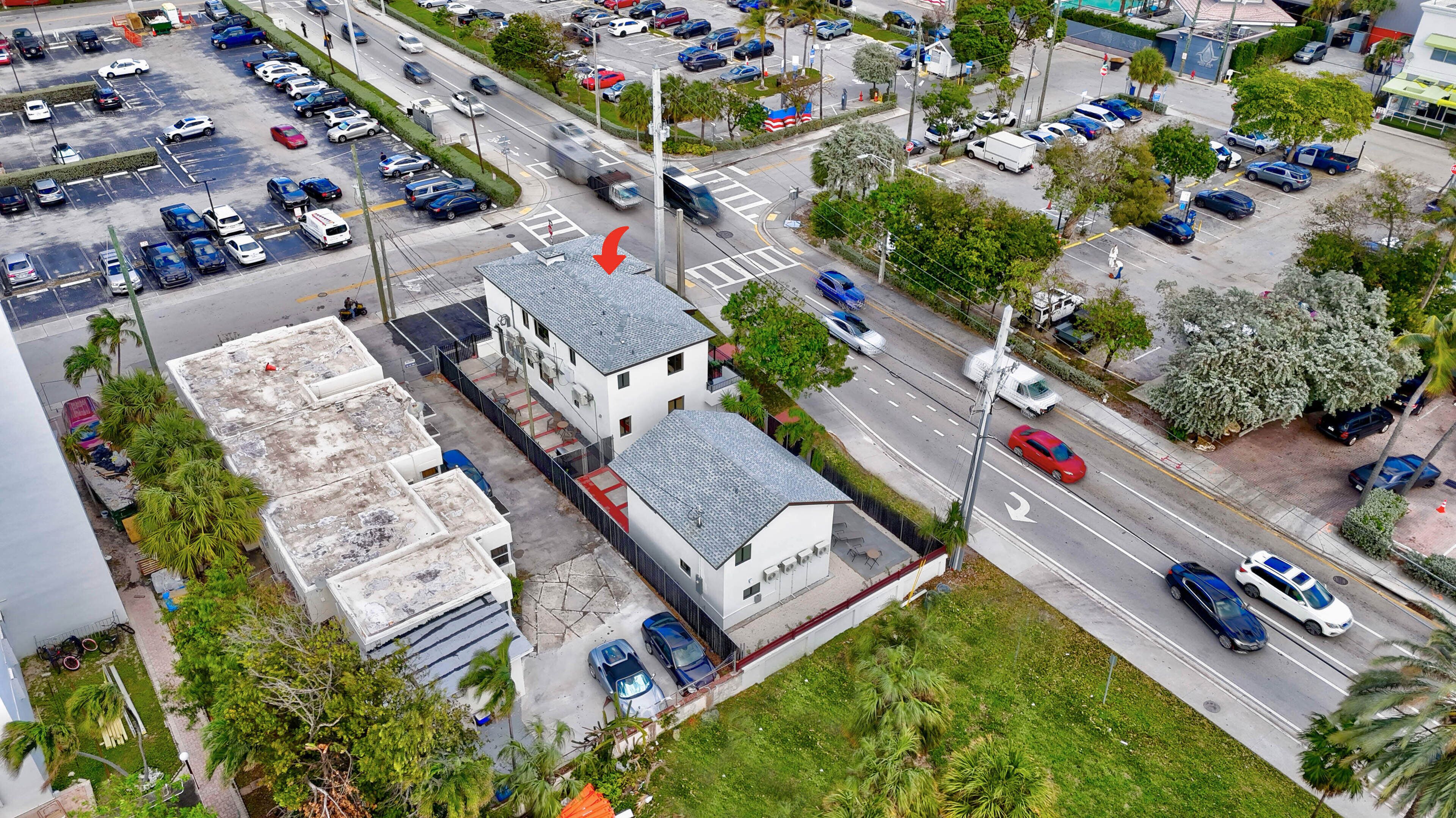 An aerial view of a parking lot with multiple cars and a building with a flat roof.