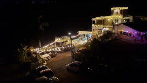 Ein Hotel mit mehreren Etagen, verziert mit Lichterketten, und ein Parkplatz mit mehreren Autos.