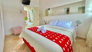 Ein Hotelzimmer mit Bett, Fernseher, Spiegel und einer Tür, die auf einen Balkon führt.