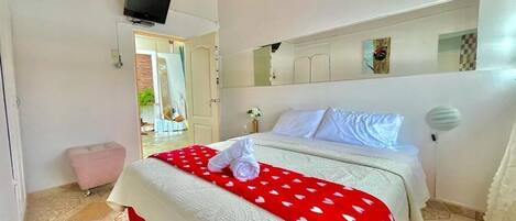 A hotel room with a bed, a television, a mirror, and a door leading to a balcony.