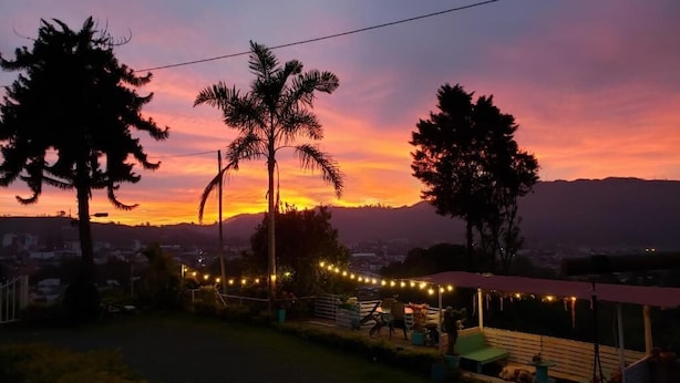 Ein Sonnenuntergangsblick mit einer Terrassenfläche, Lichterketten und einer überdachten Sitzgruppe.