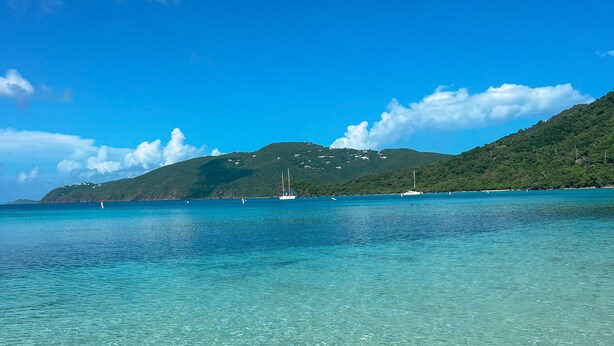 A clear view of a coastal area with a boat in the water, a hilly landscape in the background, and a clear sky. - New Listing! Island Bliss • 2BR • 3 Beds • 2 Baths (Saint Thomas)