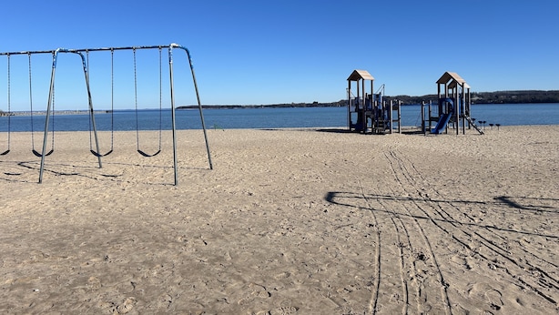 Een strand met een schommel en speeltoestellen.