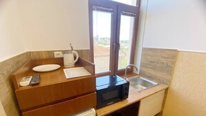 Cocina compacta con microondas, lavamanos y un refrigerador pequeño.