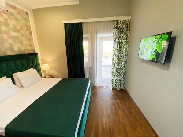 Hotelkamer met een bed, een televisie, een raam met gordijnen en een muur met een decoratief patroon.