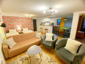 Een woonkamer met een bank, twee fauteuils, een bijzettafeltje en een pooltafel.