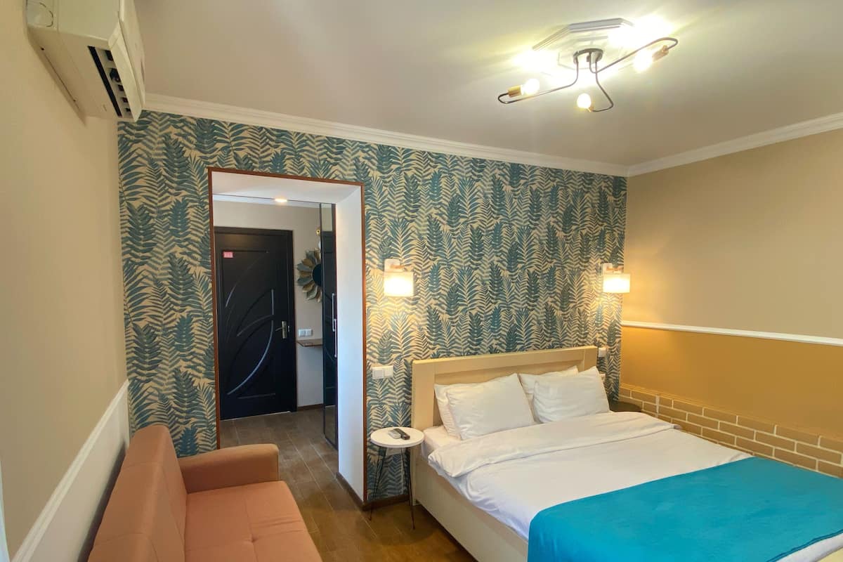 Une chambre d’hôtel comprenant un lit, une petite table, un canapé et une porte donnant sur une salle de bain.