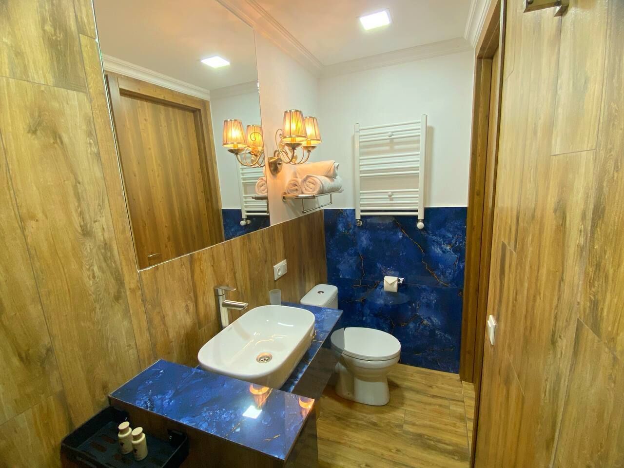 A bathroom with a wooden vanity, a white sink, a toilet, and a towel rack.